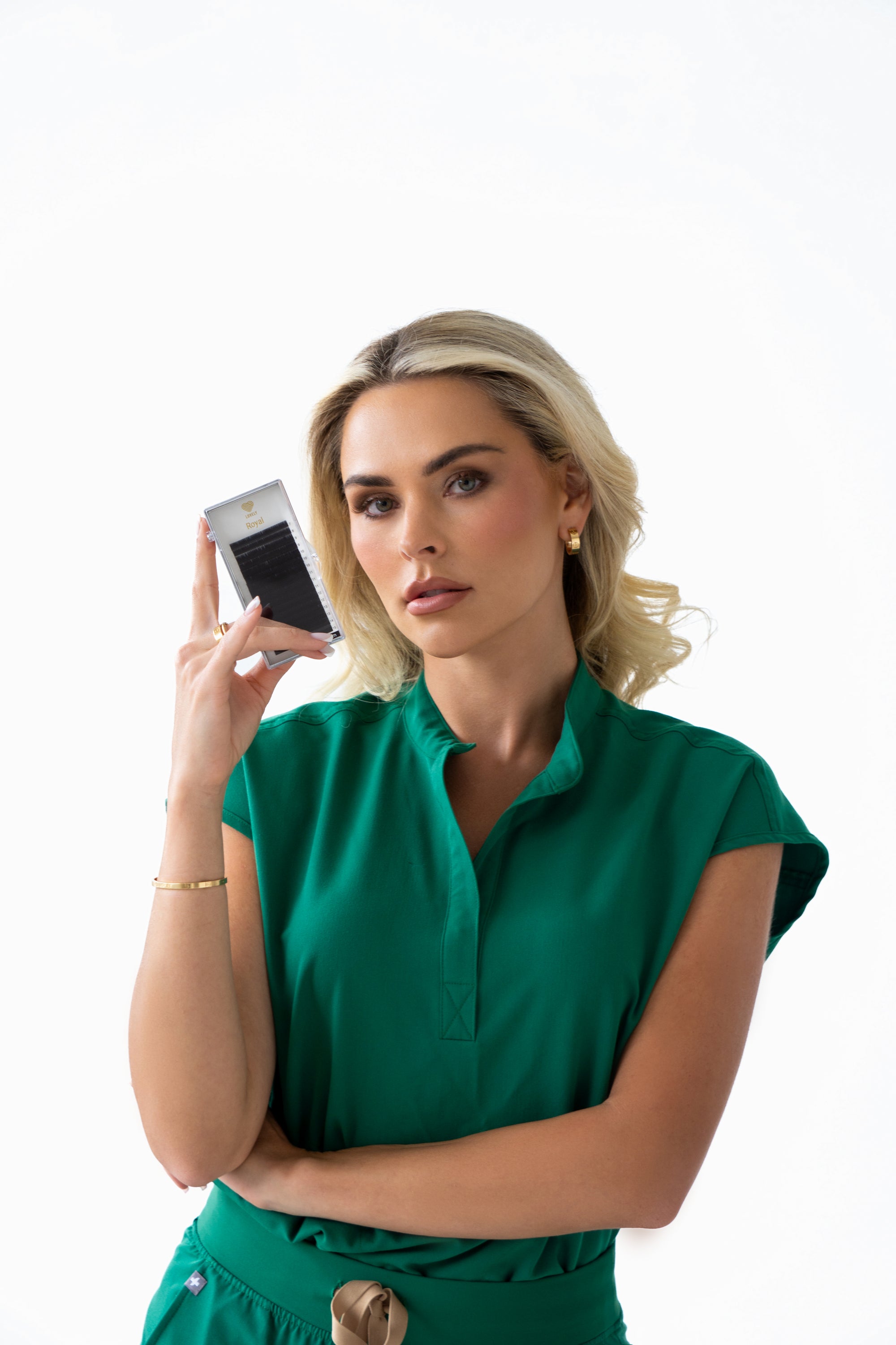 Woman in a green outfit holding a camera against a white background